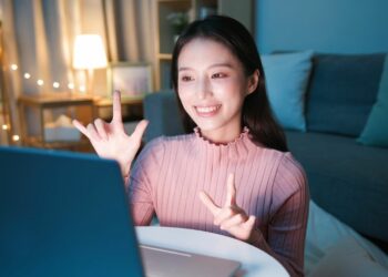 woman with love sign language in front of screen